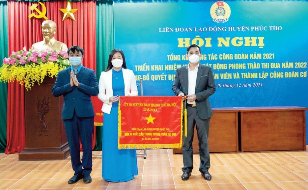 Lãnh đạo LĐLĐ huyện Phúc Thọ đón nhận Cờ đơn vị thi đua xuất sắc năm 2021 của Ủy ban nhân dân thành phố Hà Nội.  Ảnh: Mai Quý