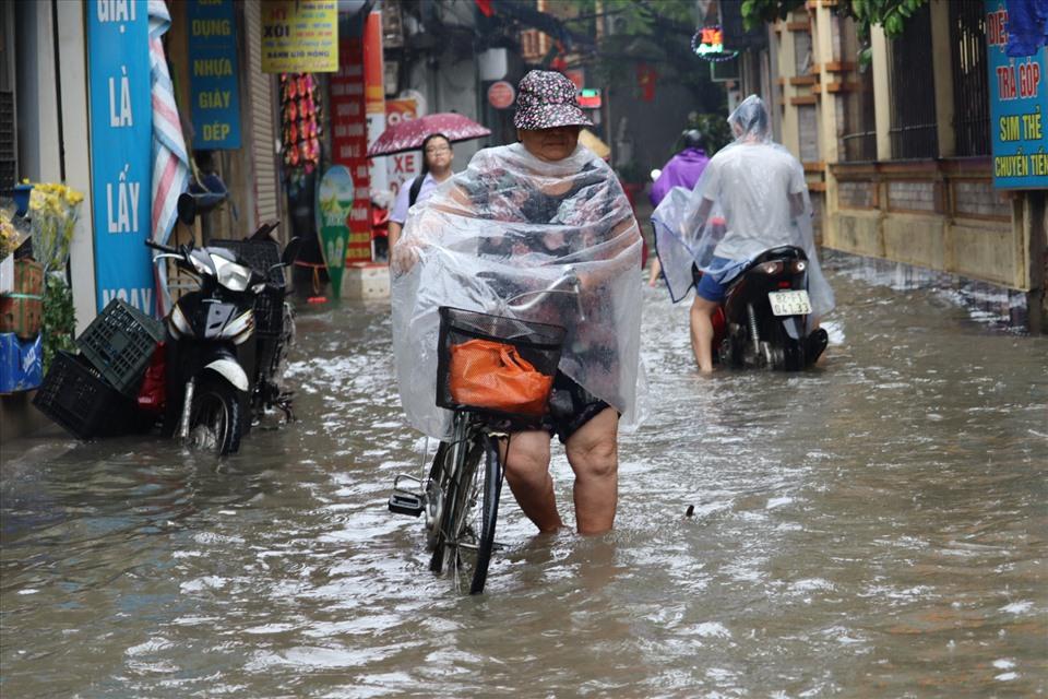 Người dân di chuyển khó khăn qua những điểm ngập sâu vì nước.