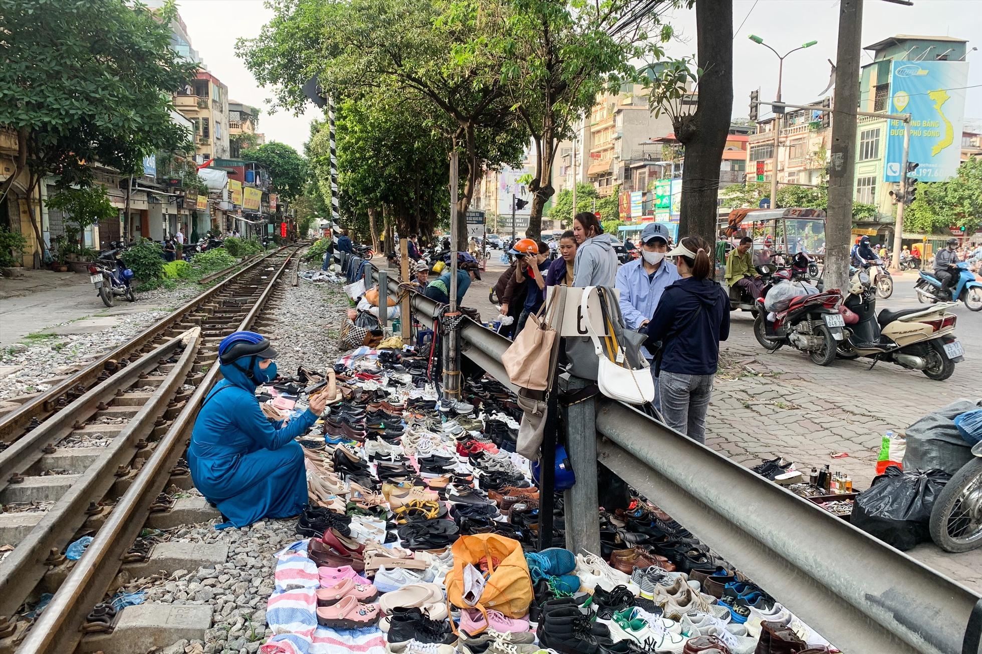 Giày, dép bày bán cạnh đường sắt, gây nguy hiểm cho người mua và người bán. Ảnh: Thu Hiền