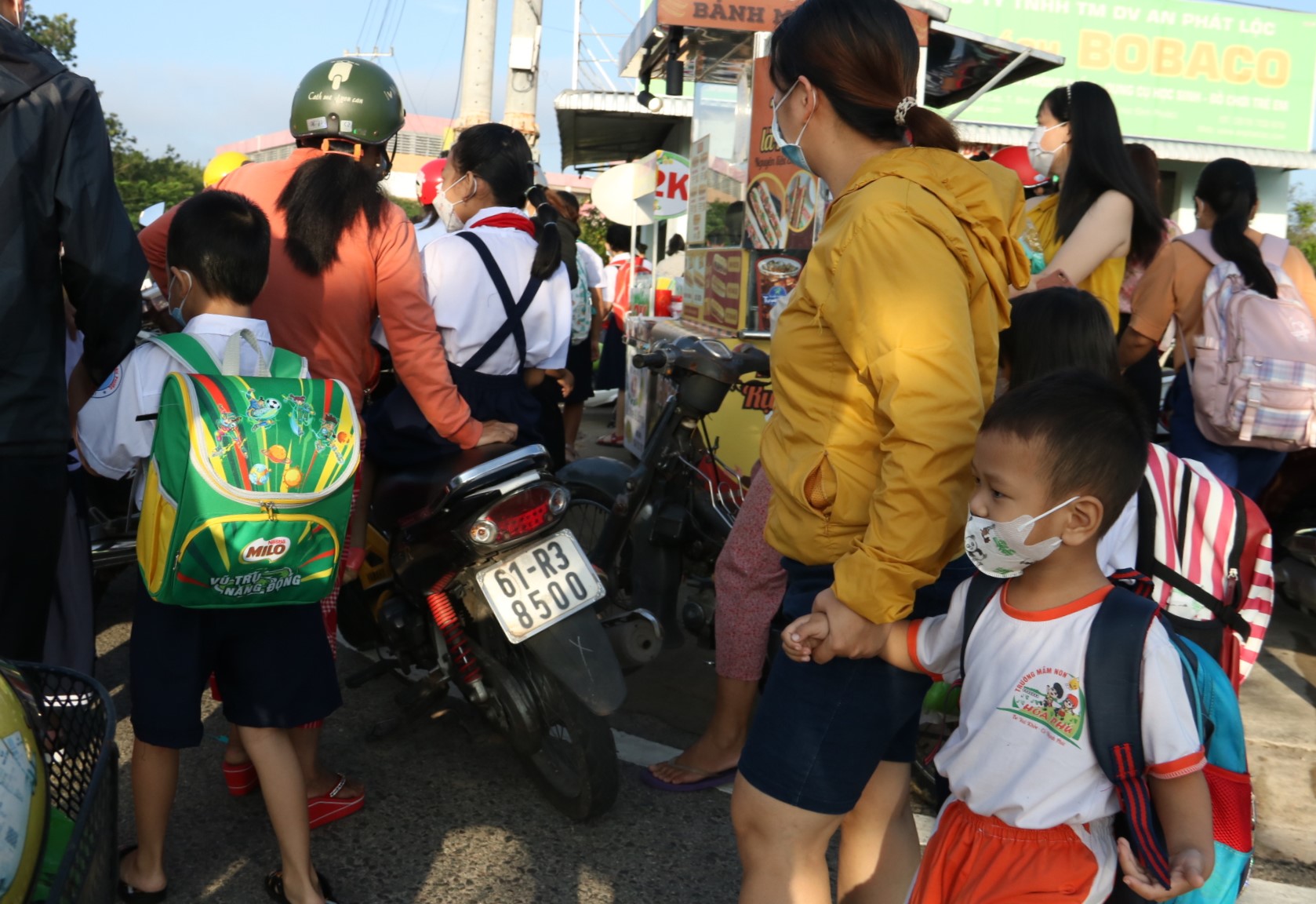 Đường vào trường bị bít lối, nhiều phụ huynh phải đứng chờ và đành bỏ xe trên vỉa hè đường Mỹ Phước Tân Vạn đễ dắt con vào trường.