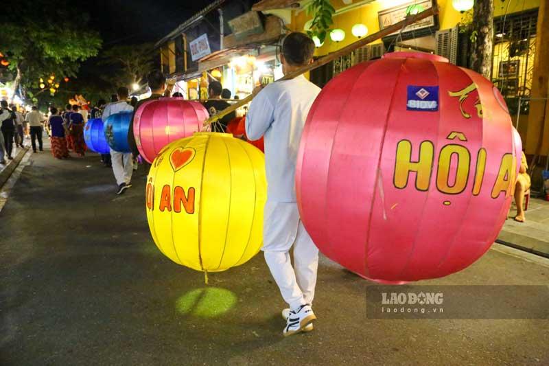 Lồng đèn Hội An với kích thước lớn được gánh trên vai, thu hút sự chú ý của nhiều du khách.