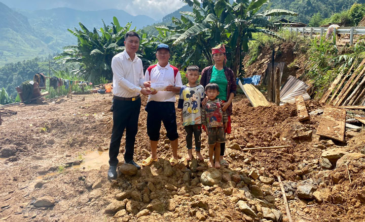 Thầy Chí Anh đại diện nhà trường trao quà cho gia đình học sinh bị thiệt hại nặng bởi sạt lở. Ảnh: NVCC