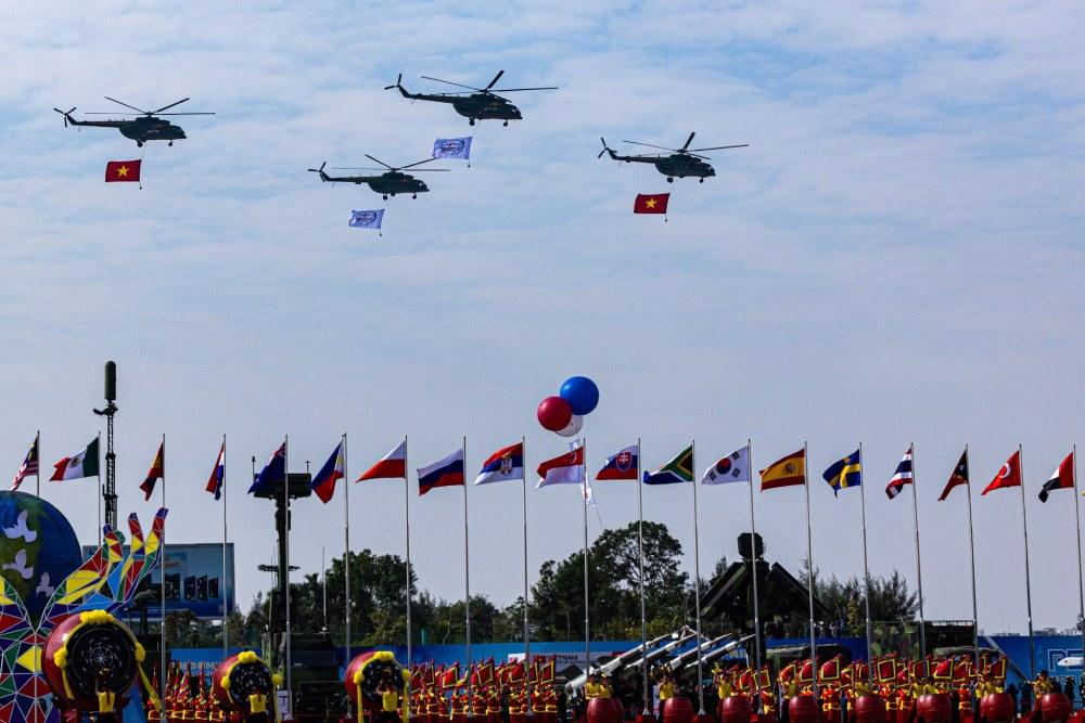 Trực thăng mang theo cờ Tổ quốc, cờ triển lãm bay qua khu vực khán đài chào mừng Triển lãm Quốc phòng quốc tế Việt Nam. Ảnh: Hải Nguyễn