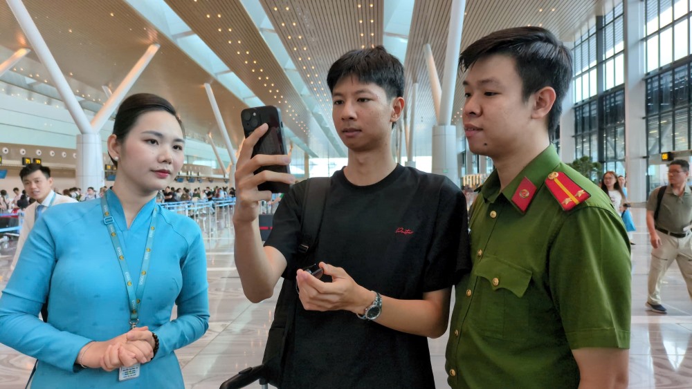 Cán bộ công an hướng dẫn người dân “check-in” bằng sinh trắc học trên ứng dụng VNeID và khuôn mặt để lên máy bay, không cần xuất trình các giấy tờ, vé máy bay như trước - Ảnh: Anh Tú