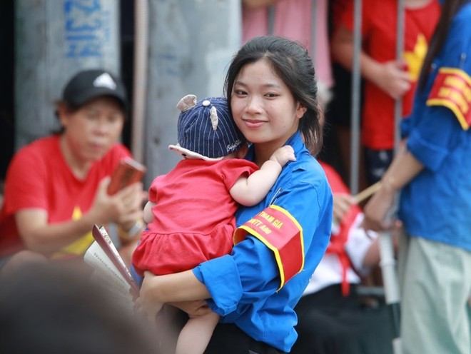 Nữ sinh viên tình nguyện hỗ trợ bế em bé sáng 30-8