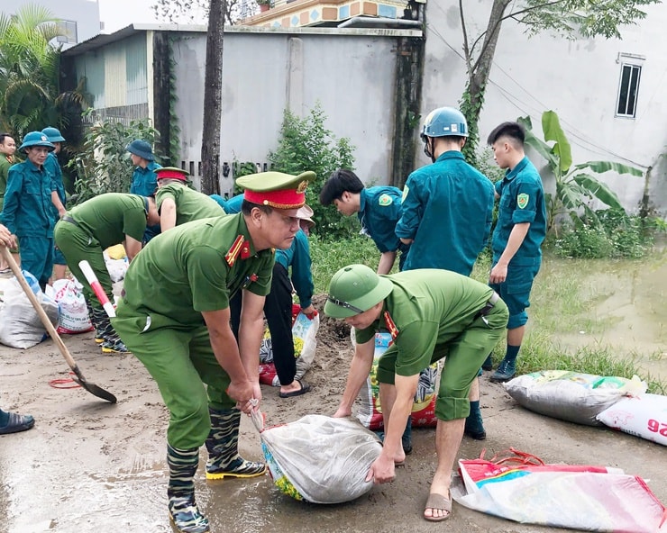 Công an và dân quân xã Quảng Bị ra sức tôn nền đê chống lũ vào khu dân cư, đồng ruộng. Ảnh: Minh Thân