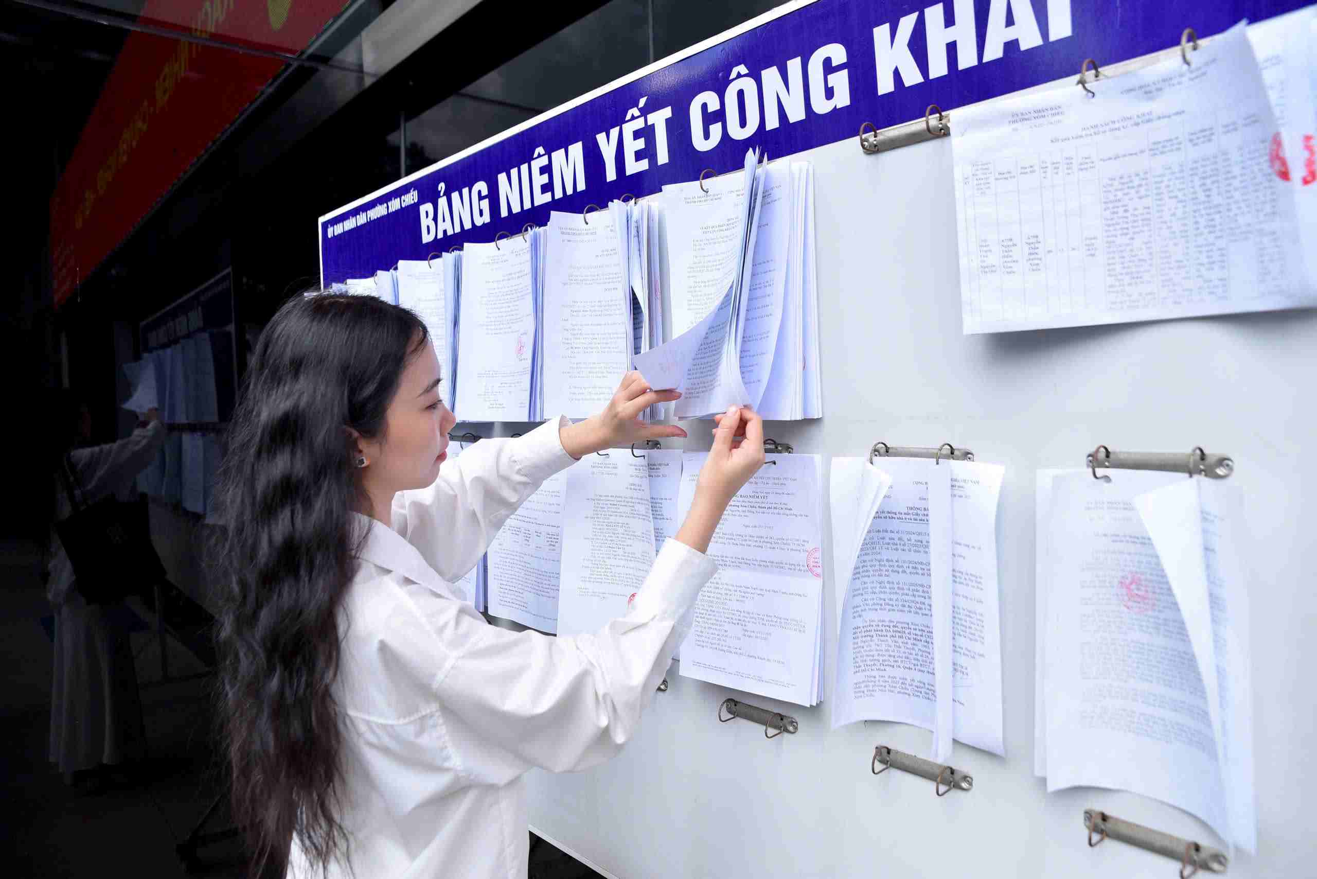 Người dân đang tìm hiểu thông tin được công khai trên bảng niêm yết của phường Xóm Chiếu. Ảnh: Minh Tâm