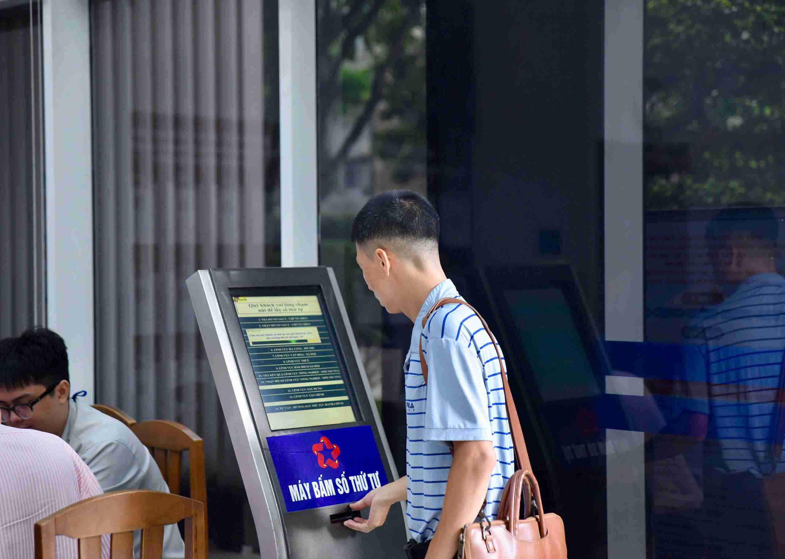 Một người dân đến bóc số thứ tự trên bảng điện tử để làm thủ tục. Ảnh: Minh Tâm