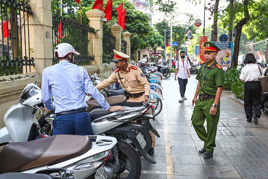 Lực lượng chức năng nhắc nhở các trường hợp dừng đỗ xe không đúng nơi quy định. Ảnh: Tô Thế