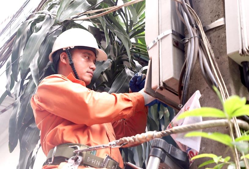 Cán bộ Điện lực Thanh Trì thay thế công tơ mới cho khách hàng sau khi phản ánh hóa đơn tiền điện tăng. Ảnh: Cường Ngô