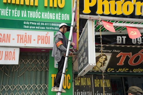 Lực lượng chức năng cắt bỏ những biển quảng cáo lắp sai quy định. Ảnh: Chánh Tiến