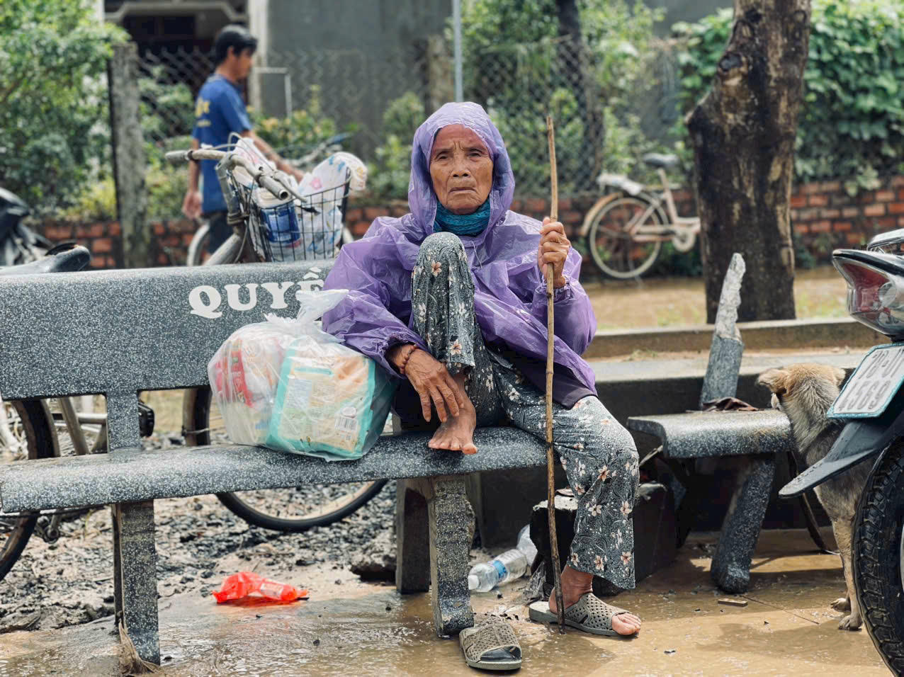 Ánh mắt người bà sau mưa lũ — sâu và buồn như chính những gì đã bị cuốn đi, khiến người nhìn cũng thắt lòng chua xót.