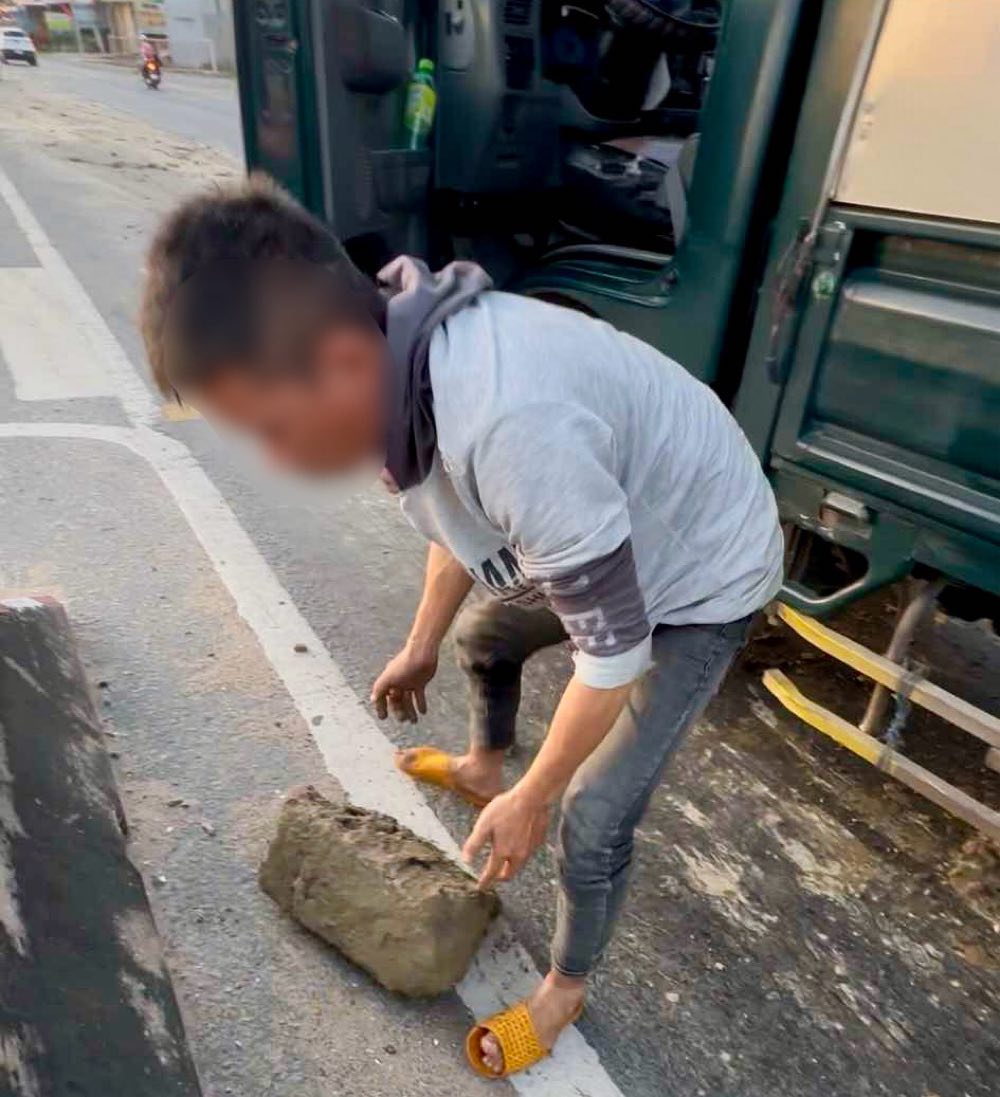 Một xe tải cán trúng hòn đá to rơi trên đường. Ảnh: Phạm Duy