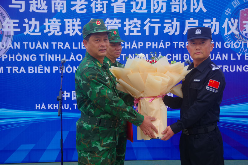 Lãnh đạo Bộ Chỉ huy Tuần tra liên hợp Bộ đội Biên phòng tỉnh Lào Cai (Việt Nam) và Lãnh đạo Bộ Chỉ huy Tuần tra liên hợp Chi đội Quản lý biên giới Hồng Hà, tỉnh Vân Nam (Trung Quốc) tặng hoa tại vạch phân định đường biên giới. Ảnh: Trung Dũng