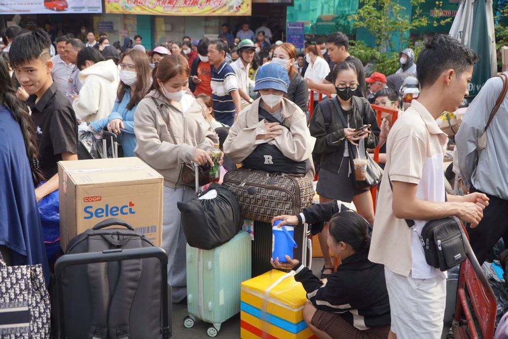 Nhiều gia đình bế theo trẻ nhỏ, tay xách túi đồ lỉnh kỉnh giữa đám đông.