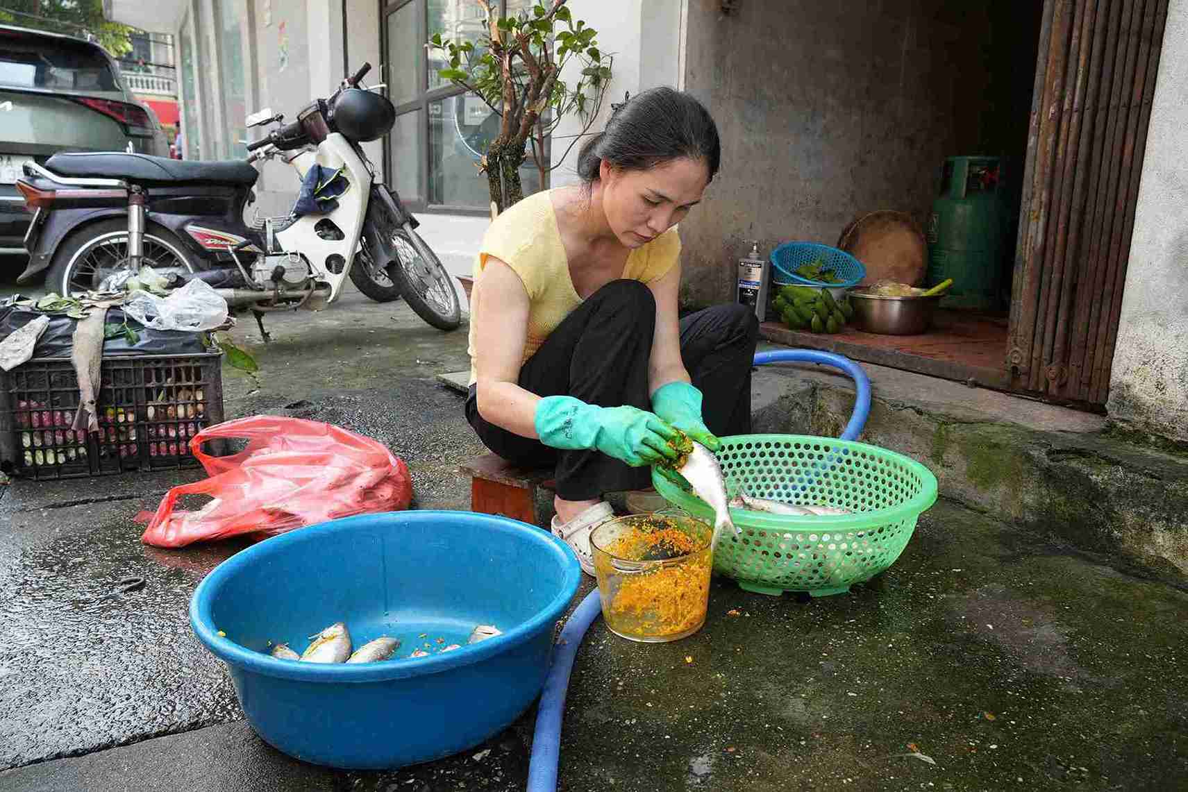 Phụ nữ địa phương ngồi làm cá mòi dưới cái nắng đầu hè.