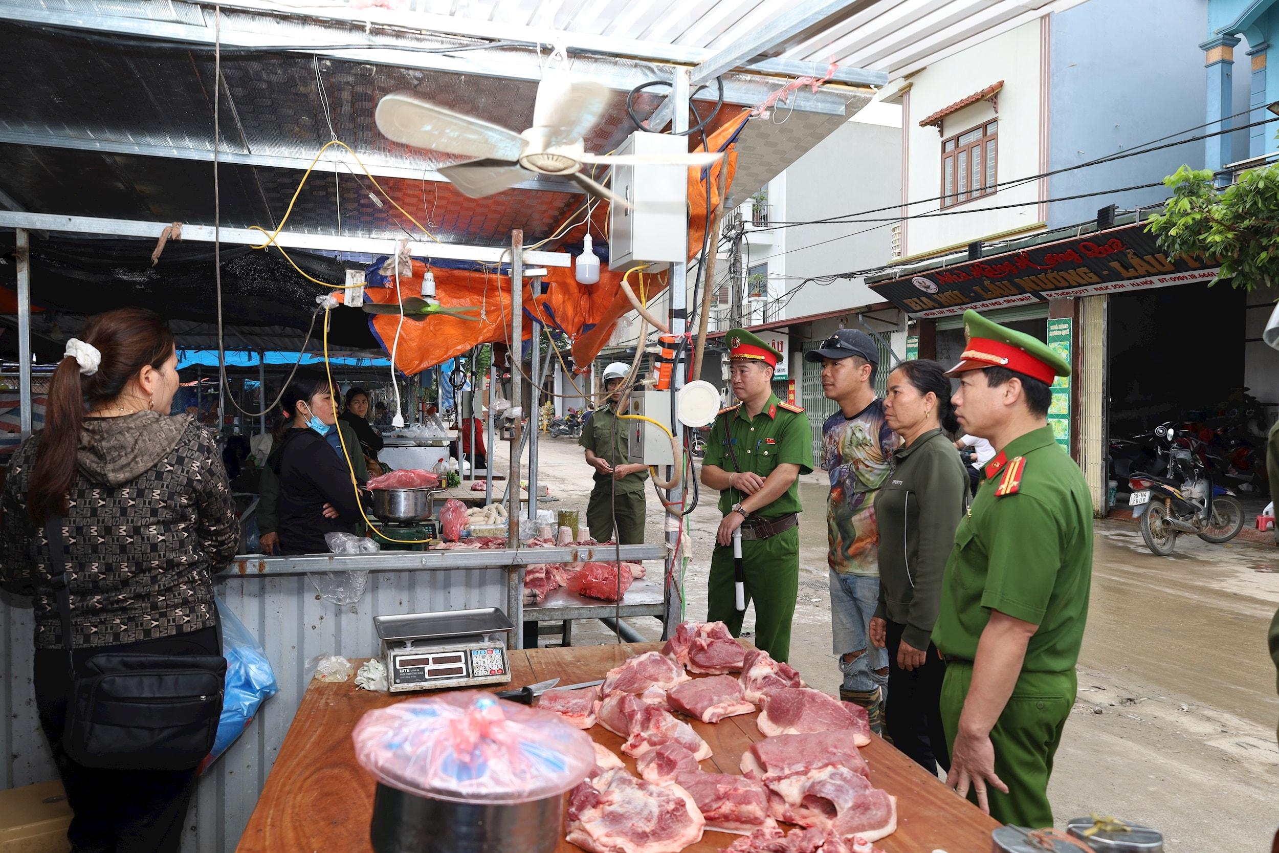 Công an xã Phúc Sơn nhắc nhở, hướng dẫn người dân kinh doanh tại chợ tạm sử dụng điện an toàn, phòng chống cháy nổ, chập điện. Ảnh: Kim Nhuệ