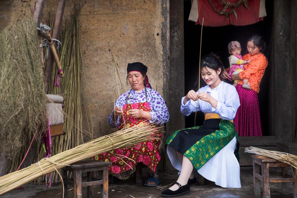 Vợ và con dâu ông Vàng Chìa Ly, một trong 11 hộ làm du lịch của thôn Thèng Pả bên nếp nhà truyền thống.