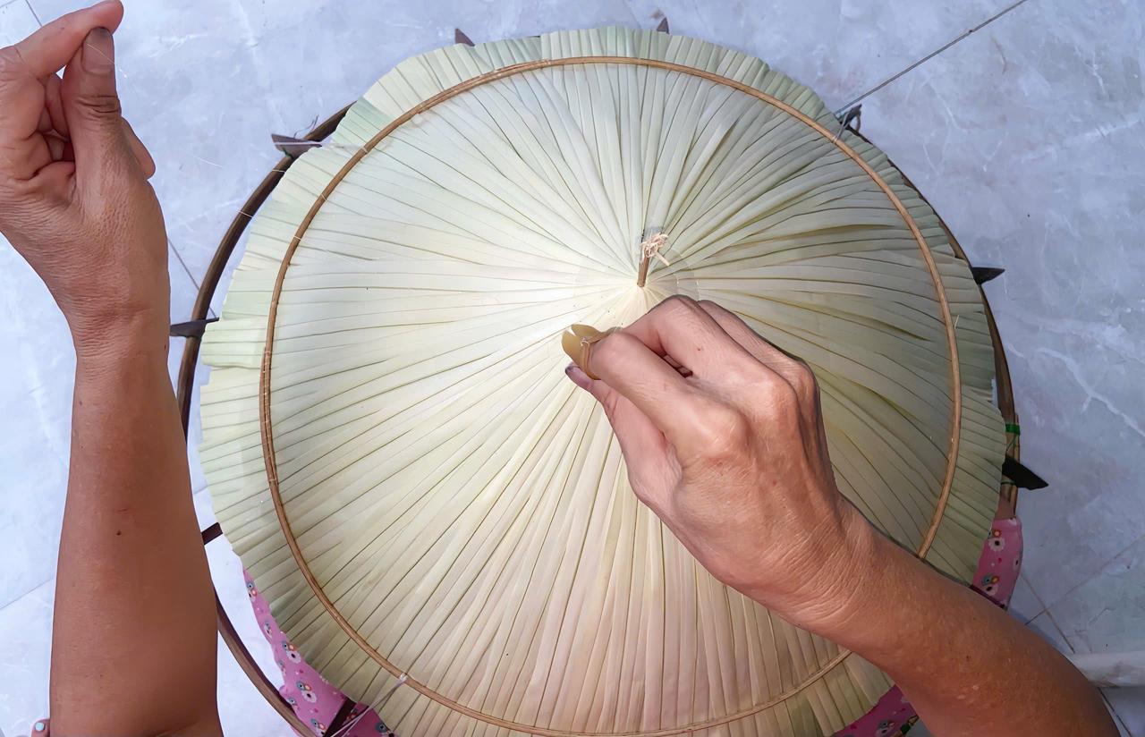 Mỗi đường kim được bà Vẩn tỉ mỉ để cố định lớp lá, quyết định độ bền và tính thẩm mỹ của chiếc nón.