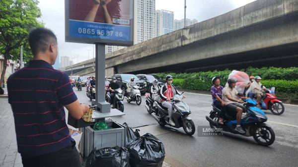 Một người dân đổ rác bên ngoài thùng rác công cộng trên đường Nguyễn Xiển. Ảnh: Minh Hạnh