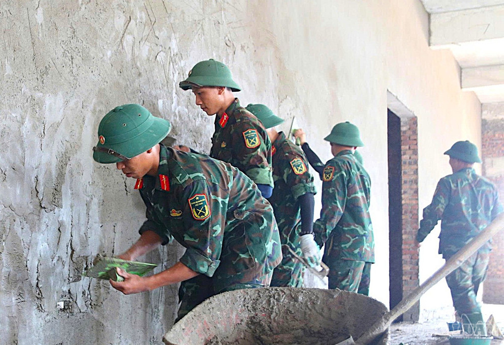 Tạm rời thao trường huấn luyện, cán bộ, chiến sĩ bộ đội trở thành những thợ phụ, thợ xây trên công trường xây dựng trường học. Ảnh: Kim Long clo_br_1.jpg